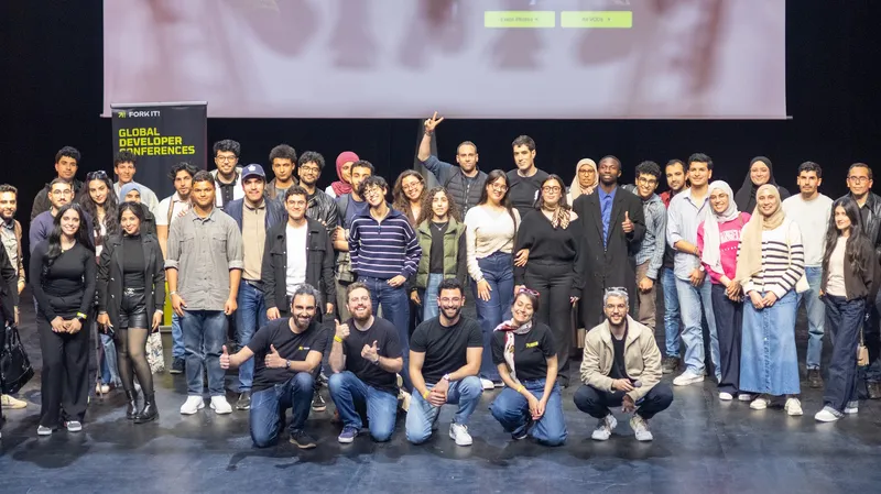 Attendees, organizers, volunteers, and speakers taking a group photo on stage