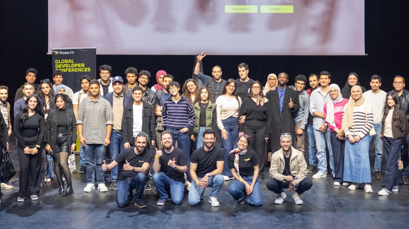 Attendees, organizers, volunteers, and speakers taking a group photo on stage